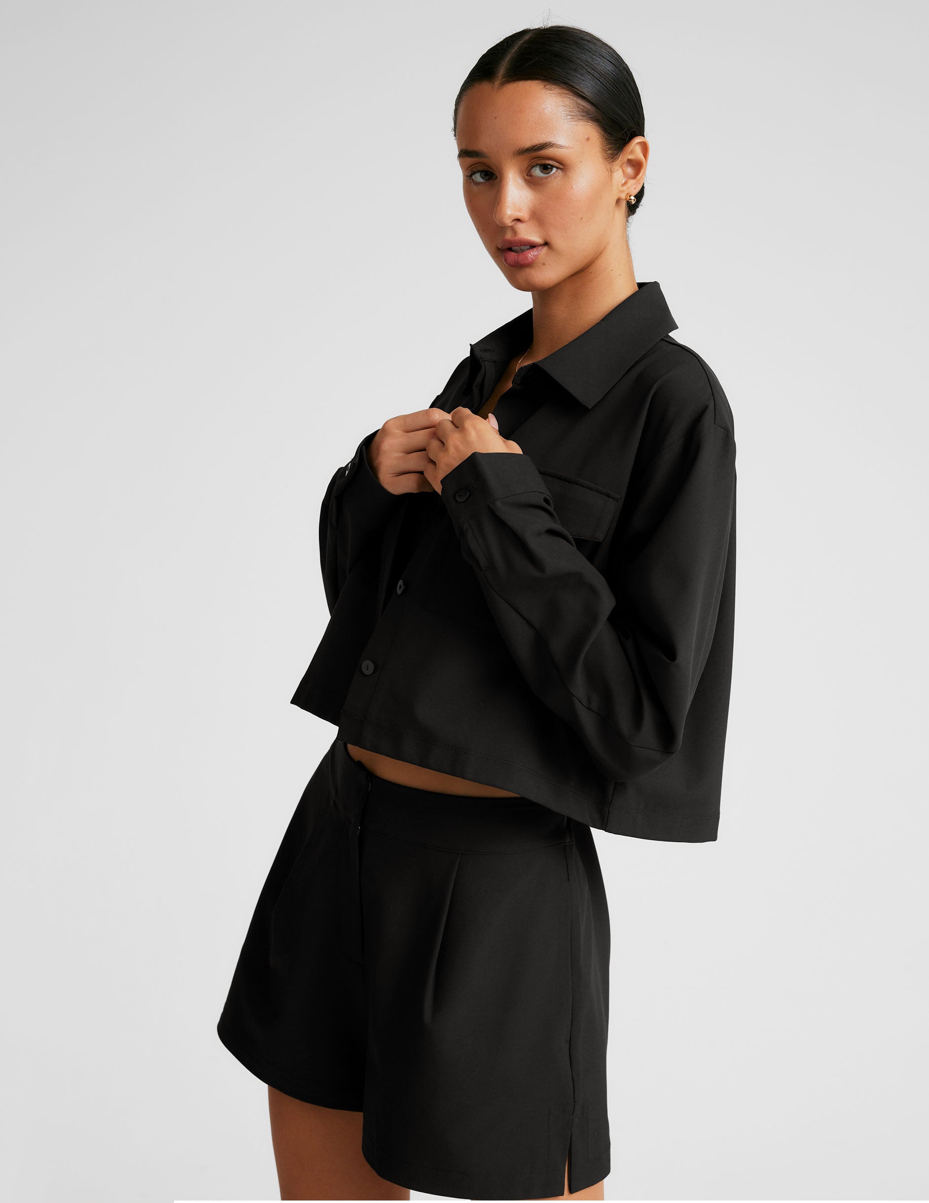 black cropped loose fitting jacket with a collar at neckline​, hidden placket with button closure at center front​, and front chest cargo pockets. 