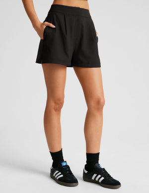 High-waisted black Midtown Trouser Short featuring front pleats, side pockets, and a relaxed A-line fit.