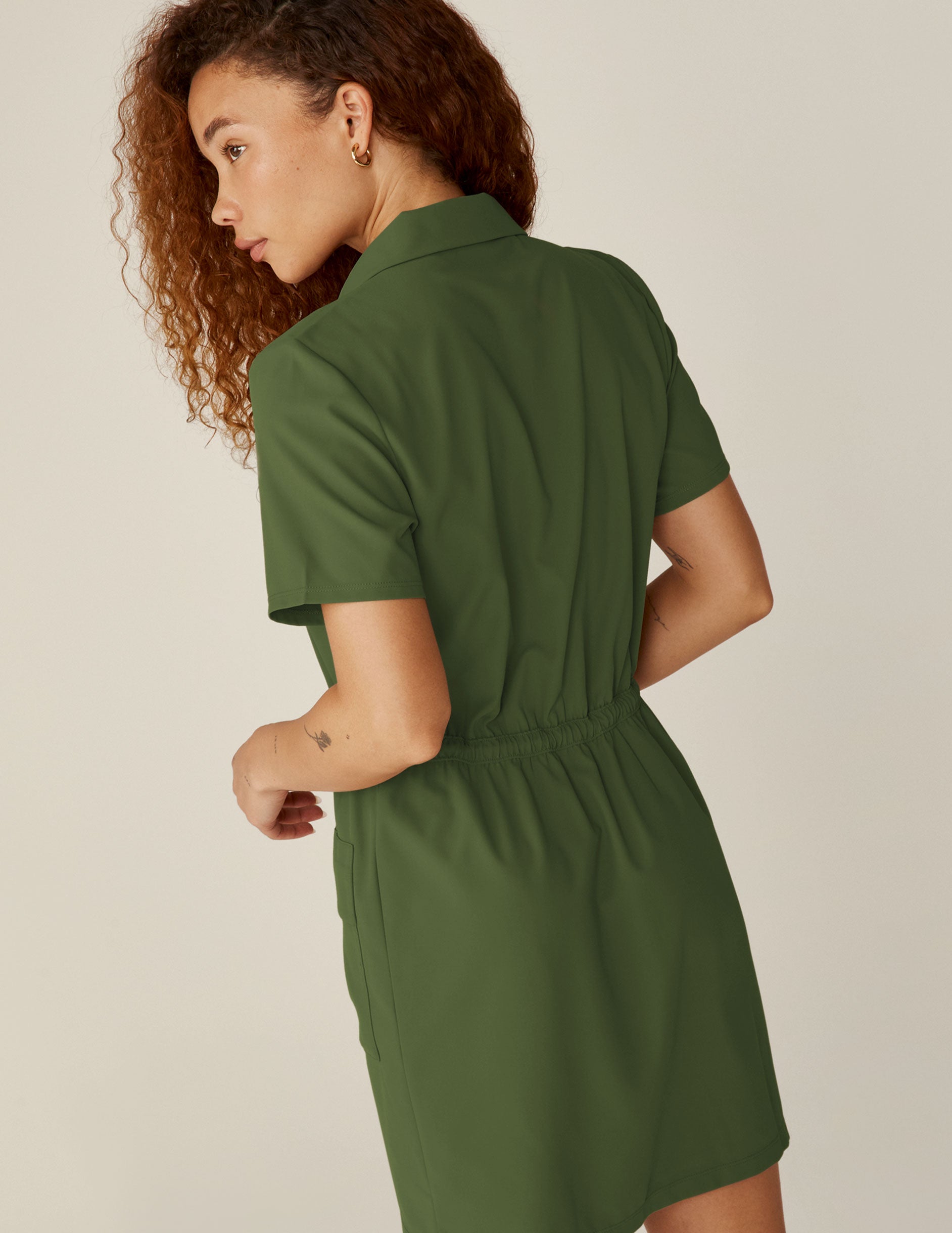 green zip-up mini dress with a drawstring at waistband and pockets.