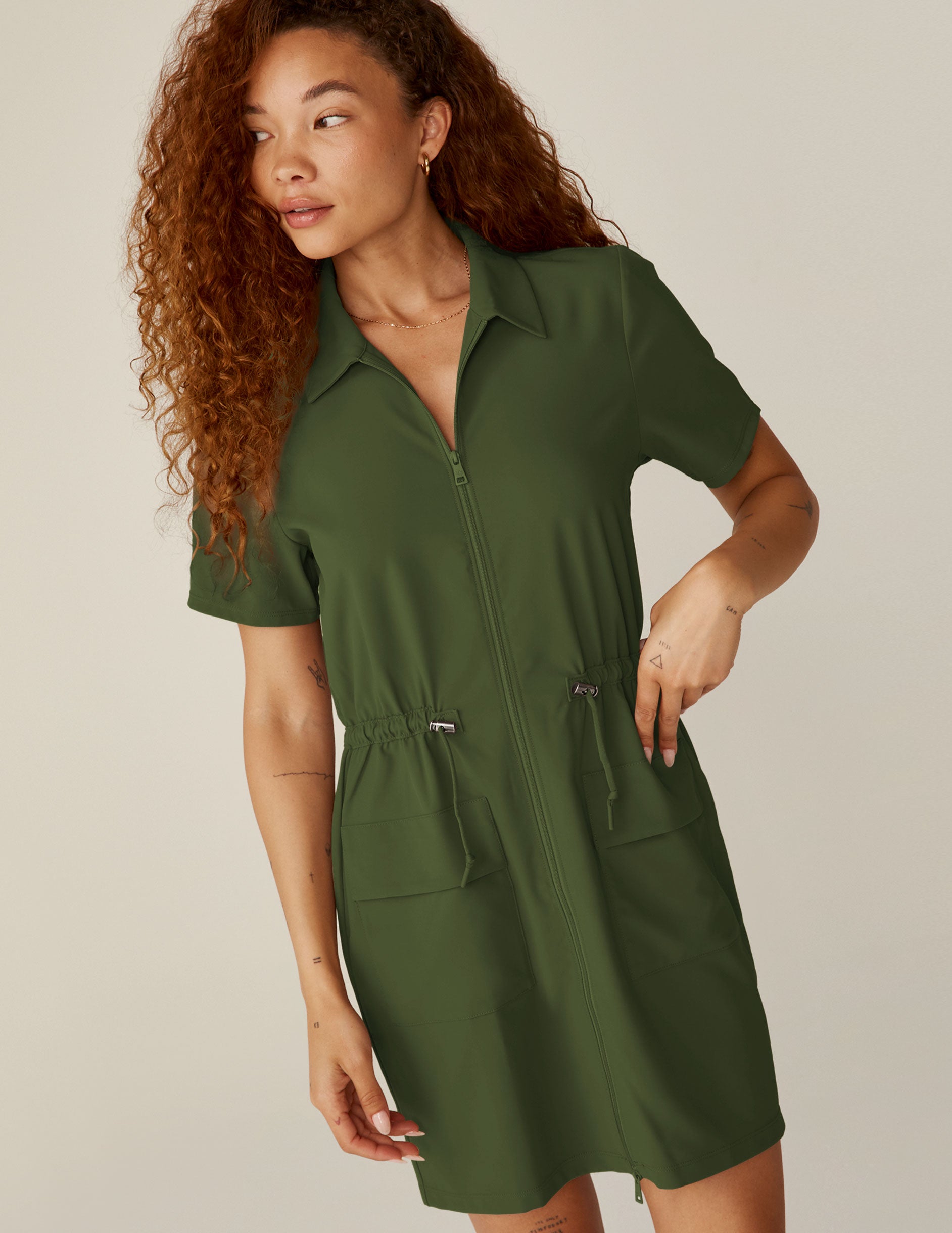 green zip-up mini dress with a drawstring at waistband and pockets.