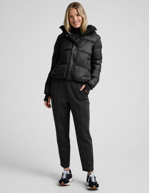 woman wearing a black puffer jacket on a plain background. 