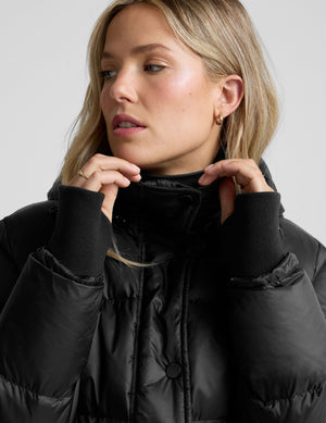 woman wearing a black puffer jacket on a plain background. 