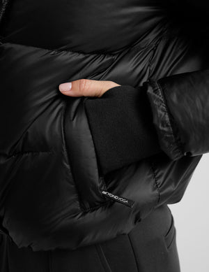 woman wearing a black puffer jacket on a plain background. 