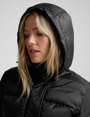 woman wearing a black puffer jacket on a plain background. 