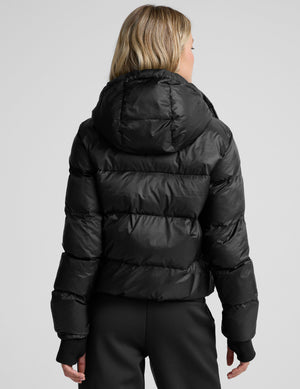 woman wearing a black puffer jacket on a plain background. 