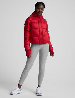 woman wearing a red puffer jacket on a plain background. 