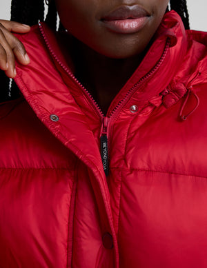 woman wearing a red puffer jacket on a plain background. 