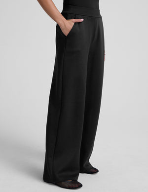 model is wearing a black sleeveless top and black spacer style pants with pockets against a plain background. 