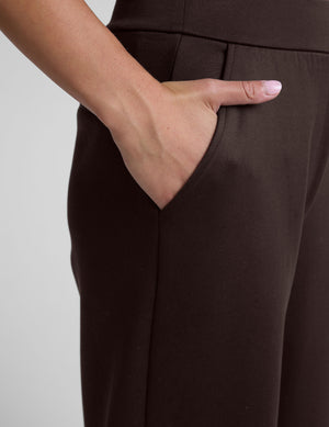woman wearing brown wide-leg pants against a plain background. 