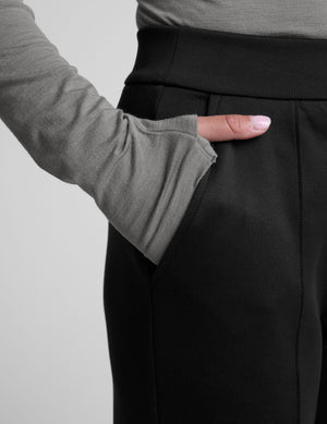 woman wearing a gray turtleneck and black tapered pants on a white background. 