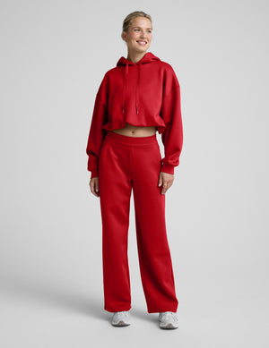 Woman wearing a red hoodie and pants set on a light gray background. 