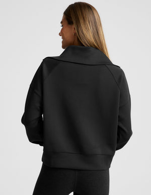 model wearing a black long length quarter zip pullover against a plain background. 
