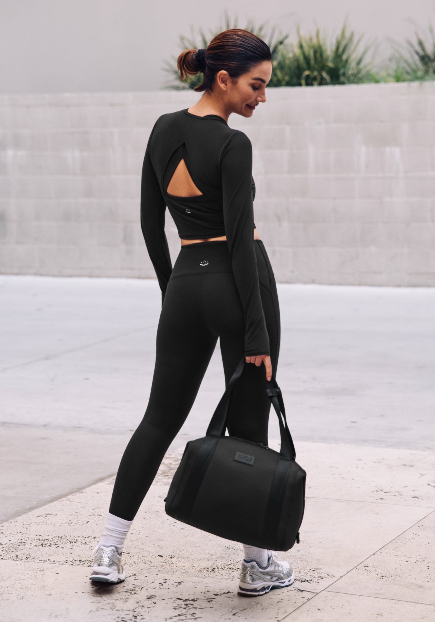 model is wearing a black POWERBEYOND Lite cropped pullover and black POWERBEYOND midi leggings. 