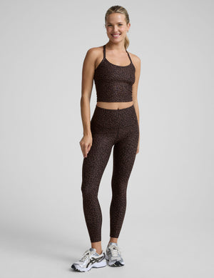 person wearing a brown leopard printed cropped tank and brown leopard print leggings on a plain background. 