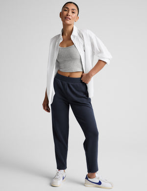 Woman wearing blue tapered ankle length pants against a plain background. 