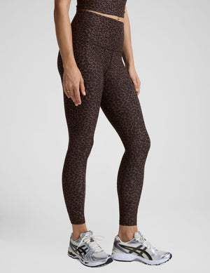 Woman wearing a brown leopard print cropped tank and leggings set on a plain background. 