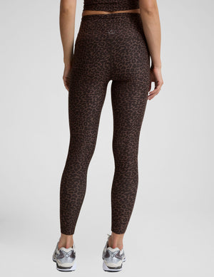 Woman wearing a brown leopard print cropped tank and leggings set on a plain background. 