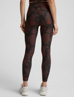 person wearing red and brown printed leggings on a light gray background. 