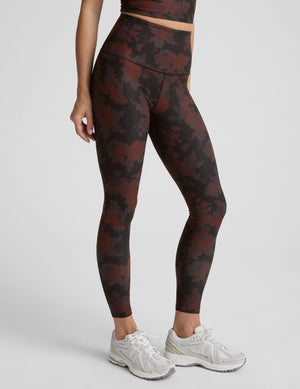 person wearing red and brown printed leggings on a light gray background. 