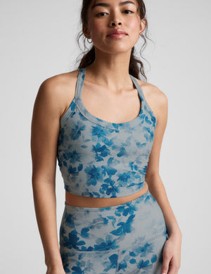 Woman wearing a blue floral sports bra and leggings on a light gray background. 