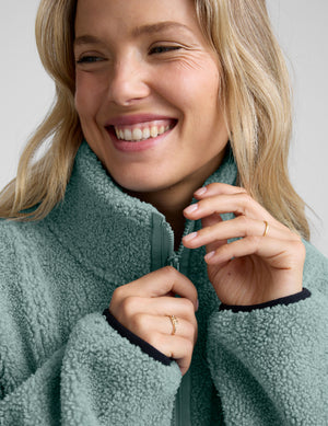 model wearing a blue zip-up fleece jacket against a plain background. 