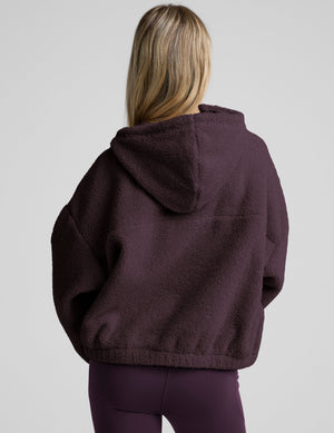 Woman wearing a purple quarter zip boucle jacket. 