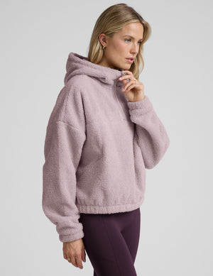 Woman wearing a pink quarter zip fleece pullover against a plain background. 