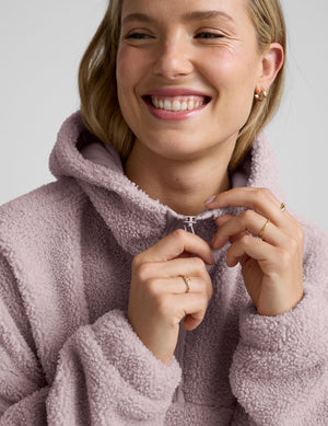 Woman wearing a pink quarter zip fleece pullover against a plain background. 
