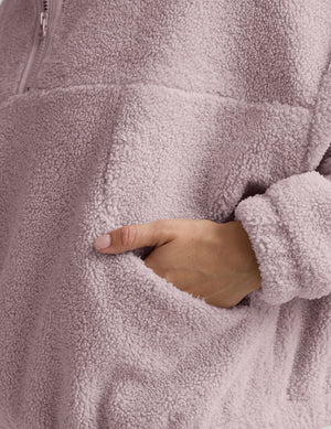 Woman wearing a pink quarter zip fleece pullover against a plain background. 