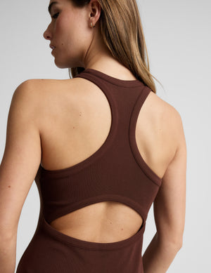 Woman wearing a ribbed brown maxi dress against a plain background. 