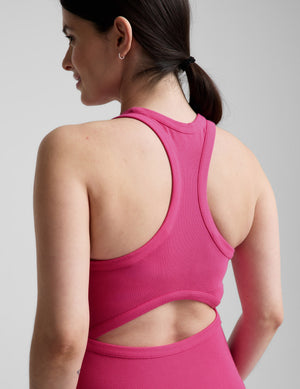 Pregnant woman wearing a pink dress on a gray background. 