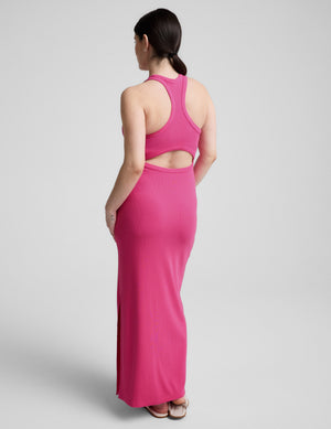 Pregnant woman wearing a pink dress on a gray background. 