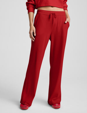 Person wearing red ribbed pants against a plain background. 