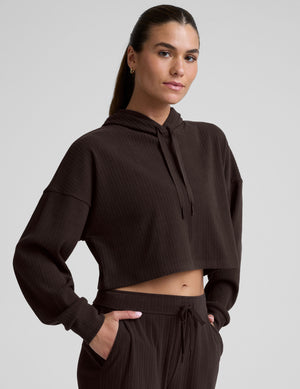 model wearing a brown ribbed cropped hoodie against a plain background. 
