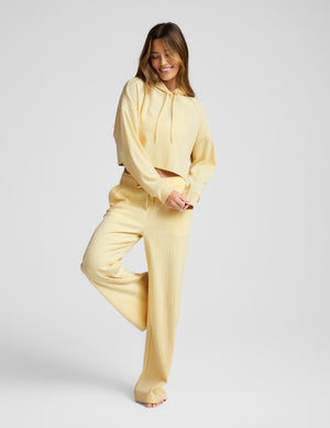 Woman wearing a yellow outfit on a plain background. 