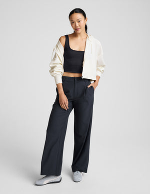 Woman wearing a blue ribbed cropped tank and blue pants against a plain background. 