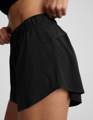 Woman wearing a black sports bra and black shorts against a plain background. 