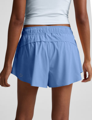 Woman wearing a blue t-shirt and blue shorts against a light gray background. 