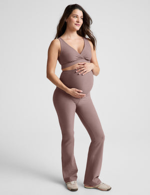 Pregnant woman wearing a brown maternity bra and pants on a white background. 