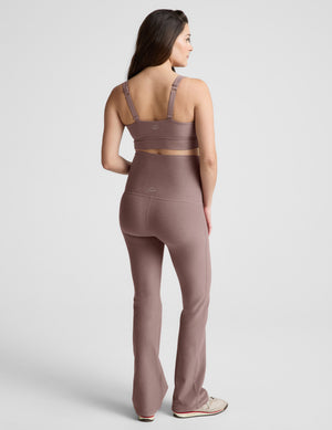 Pregnant woman wearing a brown maternity bra and pants on a white background. 