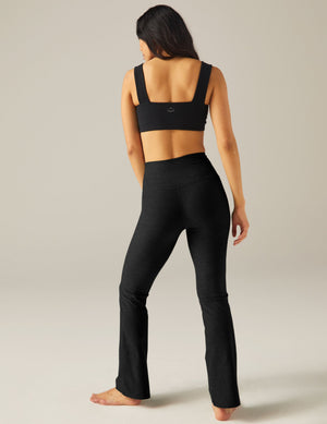 Rear view of a woman in black marled Spacedye Practice High Waisted Pant with a snug fit and flared bootcut leg.