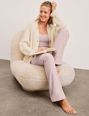 model wearing a cream cardigan and pale pink cropped tank and bootcut pants against a plain background. 