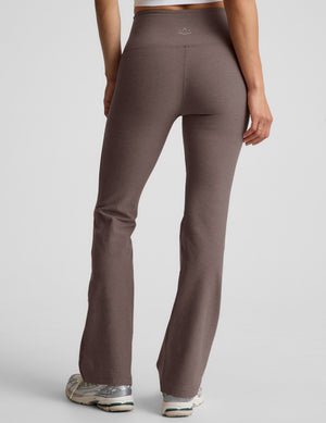 woman wearing brown high-waisted bootcut pants against a plain background. 