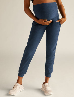 Navy Spacedye Beyond the Bump Maternity Midi Jogger with a high waistband, pockets and cuffed ankles on a model.