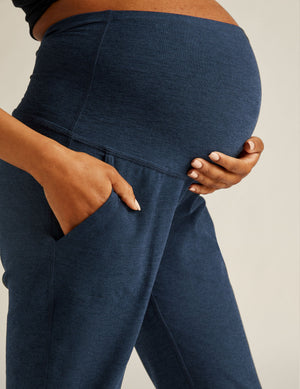 Side view of navy Spacedye Beyond the Bump Maternity Midi Jogger on a pregnant person with a hand in the side pocket.