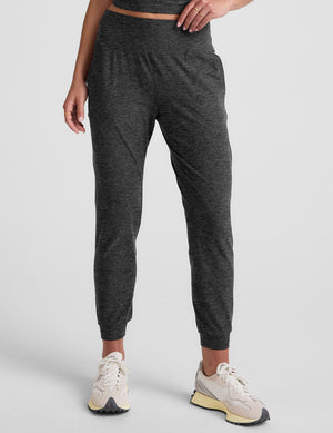 woman wearing a dark gray joggers on a plain background. 