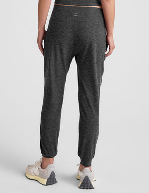 woman wearing a dark gray joggers on a plain background. 