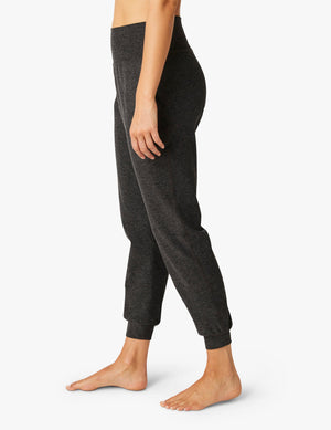 Side profile of a person wearing Spacedye Midi Joggers in black charcoal marled fabric with a high waistband and cuffed hems.