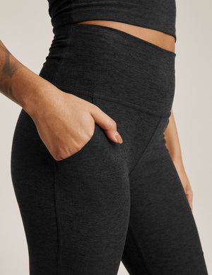 Side view of Spacedye All Day Flare High Waisted Pant in black marled fabric with a hand tucked into the functional side pocket.