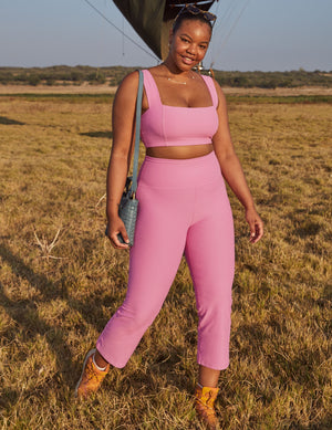 Model wears pink Spacedye Retro Cropped Pant with a high waist and cropped flare leg in an outdoor grassy field.